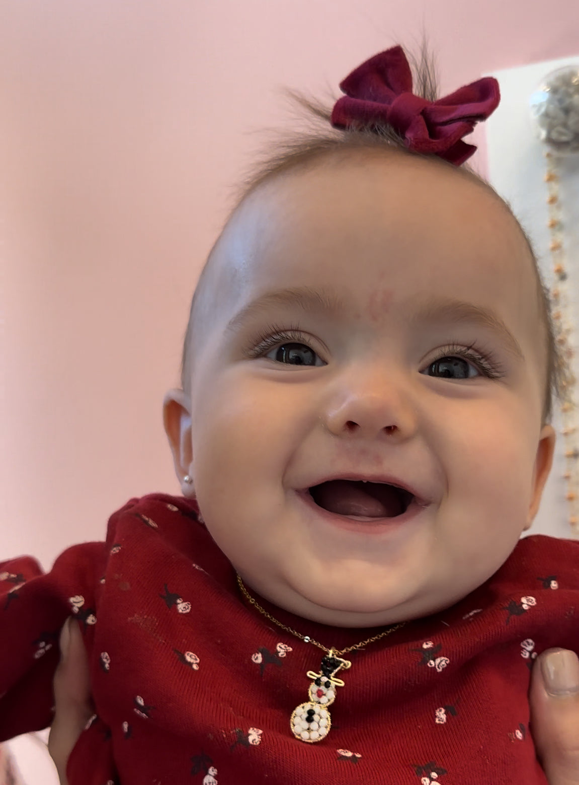 a smiling baby wearing a red shirt and a red bow